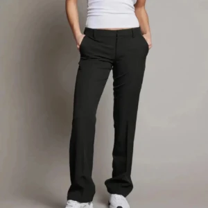 Svarta kostymbyxor - Snygga svarta kostymbyxor med en klassisk bootcut passform. De har en lågmidja och stängs med dragkedja och knapp framtill. Perfekta för en stilren look. Liten defekt därav priset, ny pris 499kr. Byxorna är i modellen vera!