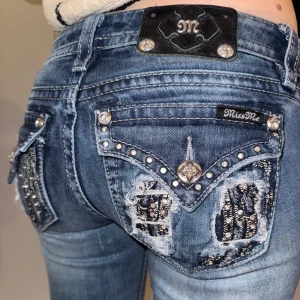 Miss Me jeans - Snygga blå jeans från Miss Me med vingar och nitar på bakfickorna. De har en låg midja och är bootcut. Midjemått rakt över ca 38 cm, Innerbenslängd ca 79 cm❤️