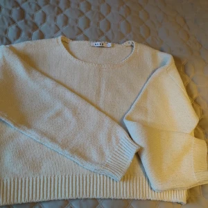 Vit stickad tröja från NA-KD i storlek S  - Säljer en vit stickad tröja från NA-KD. Tröjan har en rund hals och är croppad med ribbade kanter vid ärmslut och nederkant. Perfekt för en stilren och bekväm look.