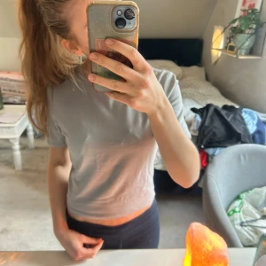 Grå croppad t-shirt från 157 - Säljer en stilren grå croppad t-shirt från 157. T-shirten har korta ärmar och en rund halsringning. Helt ny med prislappen kvar. I storlek S. 