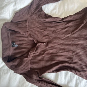 Ribbad brun tröja från Vero Moda - Säljer en ribbad brun tröja från Vero Moda i storlek S. Tröjan har klassisk krage, knappar framtill och långa ärmar. Materialet är mjukt och stretchigt, perfekt för lager-på-lager. Snygg till både jeans och kjol!