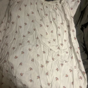 Vit blommig klänning från 157 - Supersöt vit klänning från 157 med små blommor i rosa och lila. Lätt och luftig modell med resår upptill, perfekt för varma dagar. Klänningen har en avslappnad passform och är enkel att styla med sneakers eller sandaler.