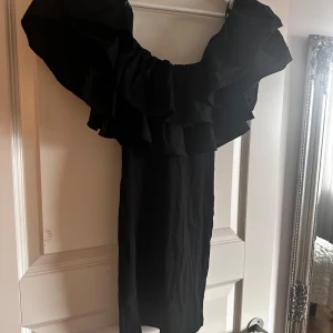 Svart offshoulder klänning med volang - Supersnygg svart kortklänning med offshoulder och stora volanger upptill.🥰
