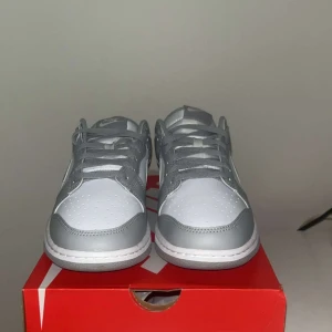 Nike Dunk Low grå/vit sneakers - Nike Dunk Low sneakers i stilren grå och vit färg. Perfekta för dig som gillar clean och modern streetstyle.