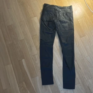 Svarta skin byxor från Vero Moda - Snygga svarta byxor från Vero Moda. De har klassisk femficksdesign och är tillverkade i ett material som ger en lätt glansig look. 