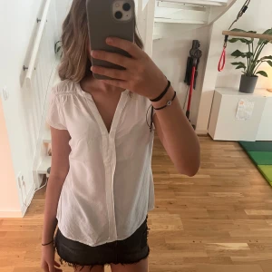 Vit kortärmad blus med v-ringning - Säljer en as fin vit skjorta/blus med korta ärmar och v-ringning. Skjortan har en enkel och stilren desig. Perfekt till jeans eller shorts för en clean look. Materialet känns lätt och luftigt. Från vero moda men tror det ej går att köpa längre. Pris kan diskuteras