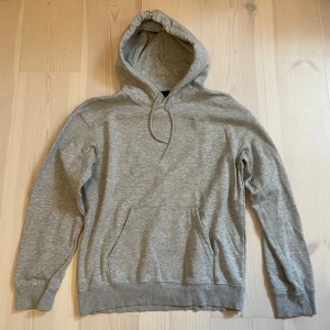 Hoodie | H&M. - En enkel och stilren grå hoodie från H&M i relaxed fit. Tröjan har huva med snörning, magficka och långa ärmar. Perfekt för chill dagar eller när du vill ha något bekvämt och snyggt. OBS: Tröjan är i storlek S men upplever den mer som en M.