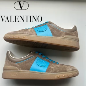 Valentino Upvillage sneakers - Snygga sneakers från Valentino Garavani i beige mocka med ljusblå detaljer och matchande blå skosnören. Skornar helt nya. Storlek 40 men passar även 41