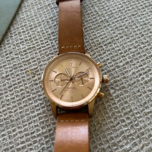 Triwa Nevil klocka med läderarmband - Stilren Triwa Nevil klocka med rund urtavla i guldton och brunt läderarmband. Urtavlan har kronograf och diskreta detaljer, perfekt för dig som gillar klassisk men modern design. Snygg accessoar som lyfter din outfit.