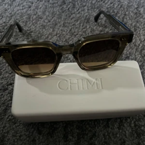 Mörkgröna solglasögon från CHIMI - Säljer ett par stilrena mörkgröna solglasögon från CHIMI med klassisk rektangulär form. Kommer med originalvitt fodral och putsduk. Perfekta för att lyfta din look och skydda ögonen mot solen😝. Nästan aldrig använda