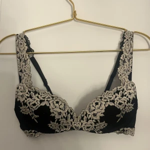 Svart Intimissimi push up bh - Supersnygg svart push up bh i storlek 70B från intimissimi. Bh:n har breda axelband och detaljerad broderad spets i vitt blommönster. Bh:n har vadderade kupor och justerbara axelband för perfekt passform. Perfekt för dig som vill ha mycket push. Bh:n är ej mycket använd eftersom den blev för liten fort.