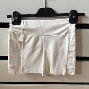 Vita tighta träningsshorts - Vita träningsshorts från Shein med fickor. De är inte det typiska träningsmaterialet utan de är mjukare. Två fickor. Perfekt för att ha under en klänning om man inte har fickor!