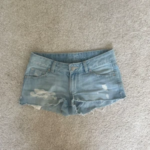 Lågmidjade jeanshorts - Snygga ljusblå jeansshorts med slitna detaljer och fransig kant med midjemått 37cm och längd (till grenen) cirka 18cm💓Skulle säga att de passar någon som bär storlek XS/S. Skickar inga bilder med dem på då de är för små 💓Märket är bortslitet, men det ser ut som hollister!