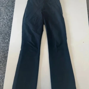 Svarta bootcut byxor från Bik Bok - Snygga svarta byxor från Bik Bok i bootcut-modell. Byxorna har en klassisk passform med utsvängda ben och är perfekta för dig som gillar en stilren look. Materialet känns mjukt och följsamt, och färgen är riktigt djup svart.