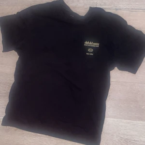 Svart t-shirt Jack & Jones La Paz - Svart t-shirt från Jack & Jones med coolt färgglatt tryck på ryggen med texten 'La Paz Baja California Sur' och tropiska växter. Framsidan har en liten logga på bröstet. Klassisk passform och rund hals. Perfekt för dig som gillar statement-plagg.