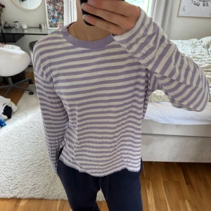 Ljuslila och vit randig långärmad tröja - Säljer en långärmad tröja med ljuslila och vita horisontella ränder. Tröjan har en rund halsringning med lila kant och är i mjuk bomull.🥰