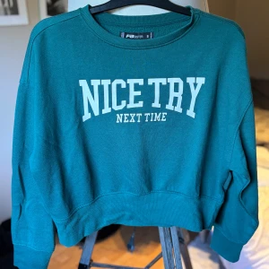 Grön sweatshirt från FB Sister - Cool grön sweatshirt från FB Sister med vit text 'NICE TRY NEXT TIME' på bröstet. Tröjan har rund halsringning, långa ärmar och en relaxed passform. Perfekt för dig som gillar en chill och sportig stil.