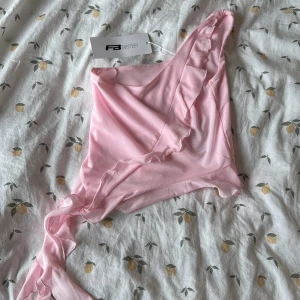 Rosa omlott topp från F3 Sister - Söt ljusrosa omlott topp med volangdetaljer och oneshoulder-design. Strl S, aldrig använd