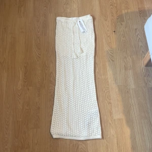 Beige stickad långkjol från FB Sister - Supersnygg beige långkjol från FB Sister med stickat, virkat mönster och dragsko i midjan. Kjolen har en bohemisk vibe och är perfekt för varma dagar. Matcha med crop top för en trendig look!
