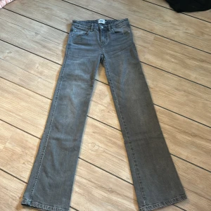 Grå bootcut jeans från lager 157, XXS - Snygga grå jeans från lager 157 i modellen 90's Boot. Byxorna har bootcut-ben och fickor med knappar på. Dom är i storlek xxs och full i benen. De har litet slitningar längst ner i benen men inget som syns. 