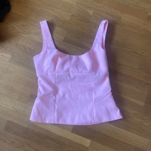 Rosa topp med rosett - Säljer denna jätte trendiga rosa toppen med breda axelband och stor rosett i ryggen. Toppen har en figurnära passform och dold dragkedja i sidan för enkel påklädning. Perfekt för dig som vill ha en snygg och trendig look. Storleken är xs men jag skulle säga x/m. Den är helt oanvänd/sprillans ny då den ej passade när jag fick hem den.