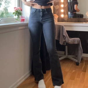 Svarta bootcut jeans från Gina Tricot - Säljer ett par svarta bootcut jeans från Gina Tricot i storlek 34. Jeansen är högmidjade med klassisk femficksdesign och har en snygg mörk tvätt. Materialet är stretchigt denim som sitter bekvämt och framhäver figuren. Jeansen har fått ett litet hål pågrund av tvätt bak på märkeslappen men man tänker ej på det.