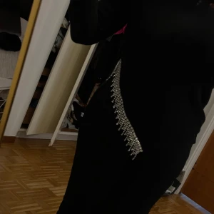 Svart stickad blus med paljettdetalj Zara - Supersnygg svart stickad klänning från Zara med långa ärmar och glittrande paljettdetalj längs ena sidan. Tröjan har en rak passform och känns både trendig och bekväm. Perfekt för dig som vill sticka ut med lite extra bling.