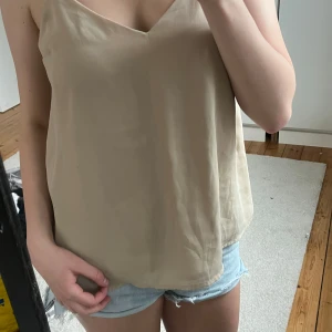 Beige linnetopp/blus från Cubus. Strl XS - Säljer en stilren beige linnetopp från Cubus i storlek XS. Toppen har tunna axelband, v-ringning och en lös passform. Gillade ej färgen på mig. 