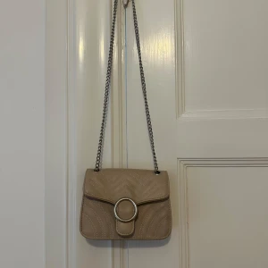 Beige axelväska med kedja - Snygg beige axelväska till salu. Kommer tyvärr inte till användning☺️