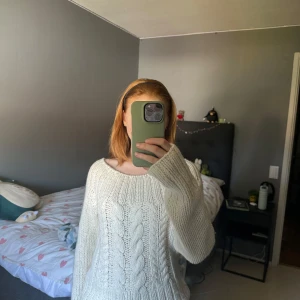 Vit stickad kabeltröja i ullmix - Säljer en chunky vit stickad tröja med grovt kabelstickat mönster och bred rund hals. Tröjan är oversized och har långa ärmar. Materialet är en mjuk mix av rami, ull och polyamid som känns både varm och cozy. Perfekt för kyliga dagar!