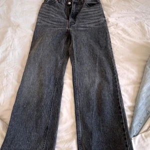 Gråa wide jeans från Monki - Säljer ett par gråa jeans från Monki med hög midja och raka, vida ben. Jeansen har klassisk femficksdesign och är tillverkade i kraftigt denimtyg. Perfekta för en avslappnad och trendig look.