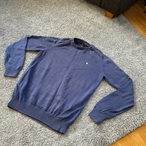 Blå stickad tröja från Morris - Snygg blå stickad tröja från Morris. Tröjan har ribbade muddar vid ärmslut och nederkant, perfekt för en stilren och avslappnad look.