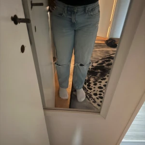 Ljusblå ripped jeans från Zara - Ljusblå jeans från Zara med raka ben och slitna detaljer vid knäna. Klassisk femficksmodell med hög midja och dragkedja. Jeansen har en relaxed fit och är tillverkade i bomull. Perfekta för en chill och trendig look.