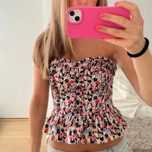 Blommig axelbandslös topp - supersöt korsettliknande topp från hm! dragkedja finns på sidan och en extra knapp tillkommer, tröjan är även i superfint skick💗💗