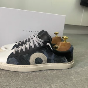 Oliver Cabell Low 1 ”Rain” - Superfeta sneakers från oliver cabell, skicket är 10/10 och det slitage som syns är menat som design. Skorna är perfekta för dig som vill vara grisch men ändå smått unik. Nypris ~3000kr mitt pris 1999:-