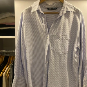 Randig oversized skjorta från Zara - Säljer en oversized skjorta från Zara i ljusblått och vitt med tunna ränder. ☺️Skjortan har klassisk krage, bröstficka, långa ärmar med manschett och knappar framtill. Den är knappt använd, önska att den passade mig bättre men tyvärr var det inget för mig.❤️