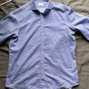 Blå mönstrad skjorta från Stenströms - Snygg blå skjorta från Stenströms med diskret blommigt mönster. Skjortan har klassisk krage, långa ärmar och knäppning framtill. Modellen är Fitted body och passar dig som gillar en mer slimmad look. Perfekt för dig som vill sticka ut lite extra.