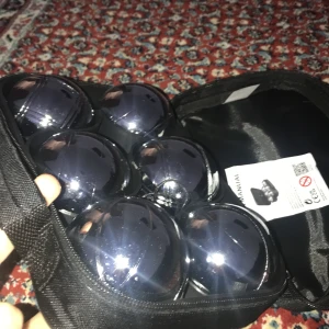 Svart väska från Stellana med bouleset - Säljer en svart, rektangulär väska från Stellana med dragkedja och handtag. Väskan innehåller ett komplett bouleset med sex metallklot, helt ny oanvänd original pris över 700kr pris kan diskuteras, skickar samma dag