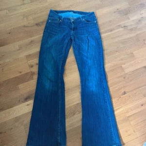 Blå bootcut jeans med utsvängda ben - Säljer ett par klassiska blå jeans med bootcut och utsvängda ben. Jeansen har låg midja och är tillverkade i denim med snygg tvätt. Perfekta för dig som gillar retrovibbar och vill ha ett par jeans som sticker ut lite extra.
