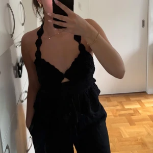 Svart virkad halterneck linnetopp - Supersöt svart halterneck topp med virkad överdel och knyt i ryggen. Toppen har broderade blommor på den utsvängda nederdelen och smala snören som ger en öppen rygg. Perfekt för sommarens alla tillfällen! Aldrig använd med prislapp kvar! Passar nog även xs beroende på önskad passform. 