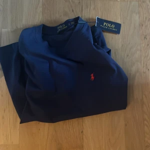 Mörkblå t-shirt från Polo Ralph Lauren - Snygg mörkblå t-shirt från Polo Ralph Lauren med klassisk röd broderad logga på bröstet. 