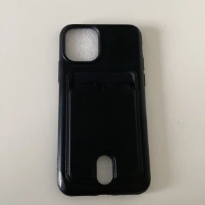 Svart plånboksfodral till mobil iPhone 11 Pro  - Svart mobilfodral med inbyggd plånbok för kort. Fodralet har en stilren design och är gjort i syntetmaterial med plats för flera kort på baksidan. Passar perfekt för dig som vill ha allt samlat i ett. Är till iPhone 11 Pro