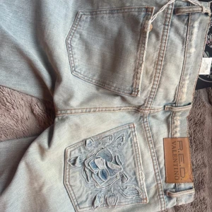bootcut lågmidjade red valentino jeans - Snygga ljusblå jeans från RED Valentino med blomma på bakfickan. innerbenslängd:87cm midjemått:40cm
