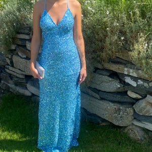 Blå glittrig långklänning med öppen rygg - Säljer en magisk blå långklänning med glittriga paljetter!  Klänningen har öppen rygg med korsade band och figurnära passform. Perfekt för bal eller andra festligheter. Nypris 4000. OBS. Det låga priset pga en liten del paljetter som lossnat vid sömnen längst ner på klänningens framsida. Kan skicka bilder på det om ni är intresserade av klänningen! Pris kan diskuteras💗