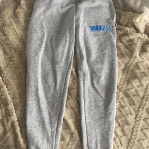Grå mjukisbyxor från Hoodrich XS - Grå mjukisbyxor från Hoodrich i storlek XS. Byxorna har elastisk midja med snörning och blå broderad logga på ena benet. Tillverkade i mjukt bomullsmaterial för maximal komfort och avslappnad stil. De sitter suuupetfint på!