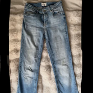 Ljusblå bootcut jeans från ONLY - Snygga ljusblå jeans från ONLY med bootcut-modell och klassisk femficksdesign. Jeansen har normal passform, dragkedja och knapp framtill samt tydliga slitningar för en cool look. Perfekta till sneakers eller boots. Ser midwaist ut men är lågmidjade, kan vara rätt så korta så de passar en kort person men annars är de strl 32 / xs