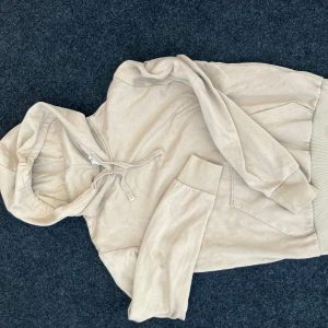 Beige hoodie från Divided  - Snygg beige hoodie från Divided i storlek XS. Tröjan har huva med snörning, magficka och ribbade muddar vid ärmslut och nederkant. 