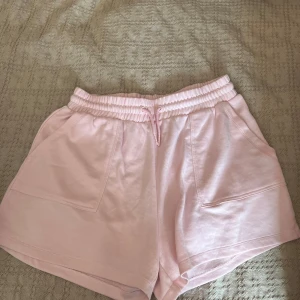 Ljusrosa shorts från Primark - Supermjuka ljusrosa shorts från Primark med elastisk midja och snörning. De har två stora fickor framtill och är perfekta för chill dagar. Tillverkade i bomull för en skön och avslappnad känsla.