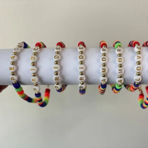 Pride armband med bokstavspärlor - 🏳️‍🌈🏳️‍🌈🏳️‍🌈PRIDE MÅNAD 🏳️‍🌈🏳️‍🌈🏳️‍🌈               Färgglatt armband med regnbågsfärgade platta pärlor och vita bokstavspärlor med guldtext, där det står ord som PRIDE, PEACE, AMOR och LOVE. Armbandet har även små guldfärgade pärlor och ett metallspänne. Perfekt accessoar för att sprida kärlek och pepp.                                       1 st för 80 kr                                                                 3 st för 170 kr 