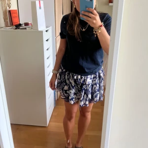 Mönstrad blåvit volangkjol - Supersöt kort mönstrad volangkjol i blått och vitt. Kjolen har omlottkänsla och resår i midjan för skön passform. I stl S från Zara🫶🫶